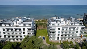 A modern apartment building with multiple balconies, a central courtyard, and a view of the sea. - Stylish Studio with Air Conditioning | Near the Beach | Parking (Mielno)
