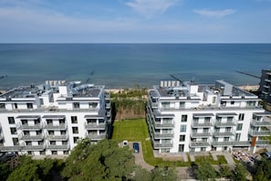 A modern apartment building with multiple balconies, a central courtyard, and a view of the sea.