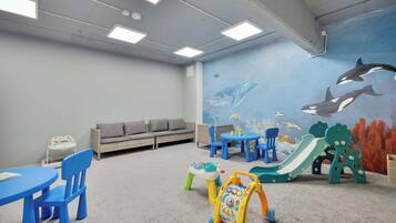 A children's play area with a slide, a walker, and a mural of marine life.