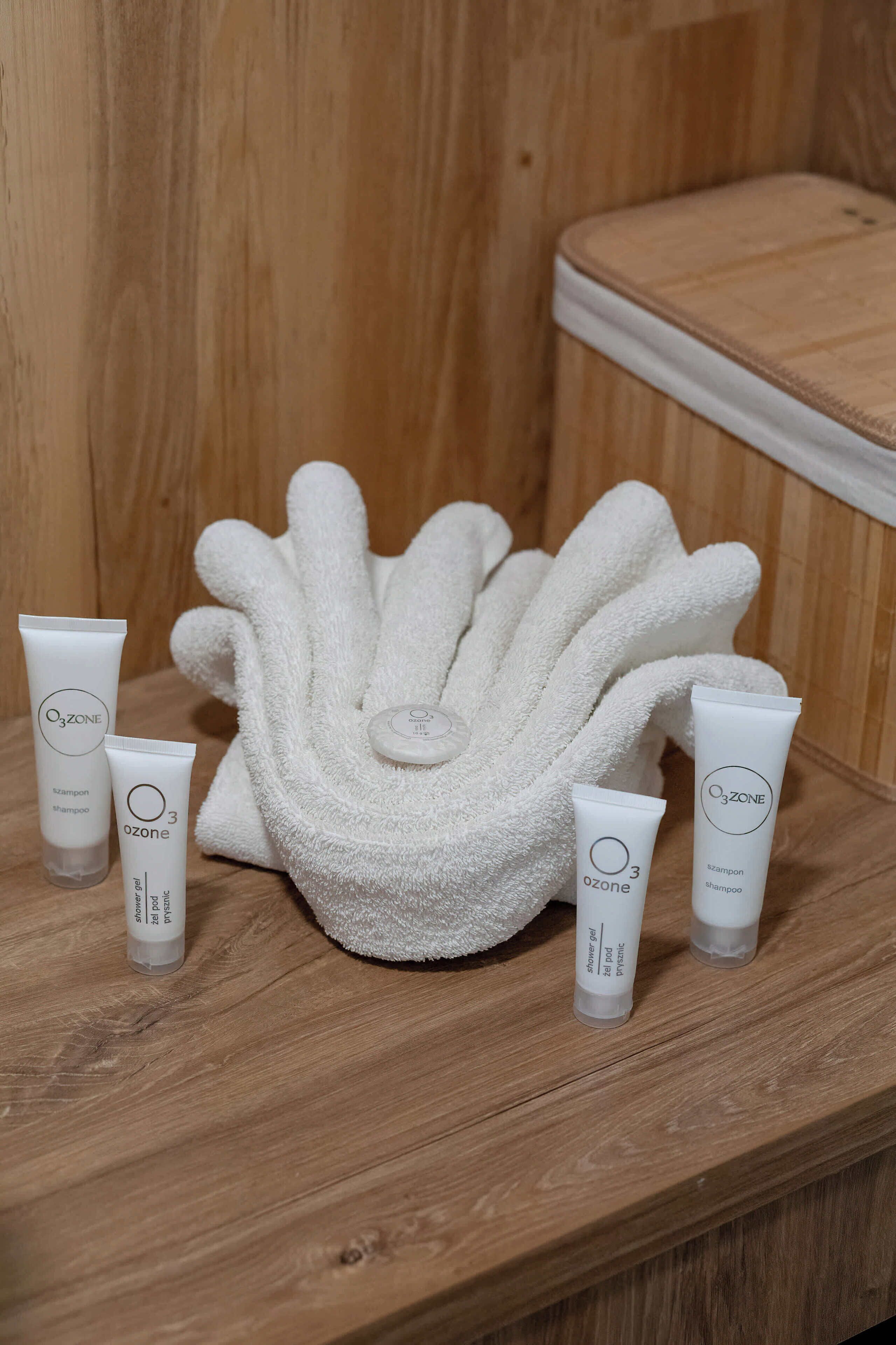 A wooden shelf with a white towel and three Ozone shampoo tubes.