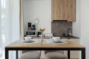 A modern kitchen with wooden cabinets, a microwave, a coffee maker, and a vase with flowers on the dining table.
