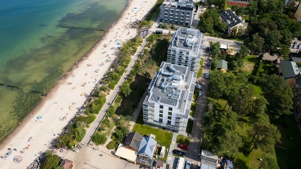 An aerial view of a coastal area with a beach, buildings, and greenery. - Stylish Studio with Air Conditioning | Near the Beach | Parking (Mielno)