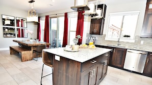 Una cocina moderna con una isla central, armarios de madera oscura y un lavavajillas de acero inoxidable.