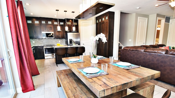 Una cocina moderna con armarios de madera oscura, electrodomésticos de acero inoxidable y una mesa de comedor de madera para cuatro comensales.