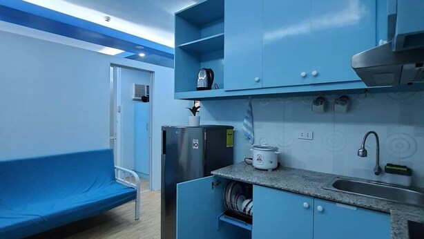 A compact kitchen with blue cabinets, a sink, and a countertop. - Mistow BriaCondo City Center Area (Cagayan de Oro)