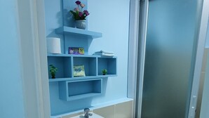 A bathroom with a white sink, blue cabinets, a toilet, and a shower area. - Mistow BriaCondo City Center Area (Cagayan de Oro)