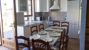 A kitchen with a dining table set for six, equipped with a microwave, stove, and sink.