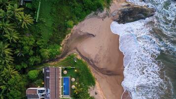 An aerial view of a beach with a small building and a pool.
