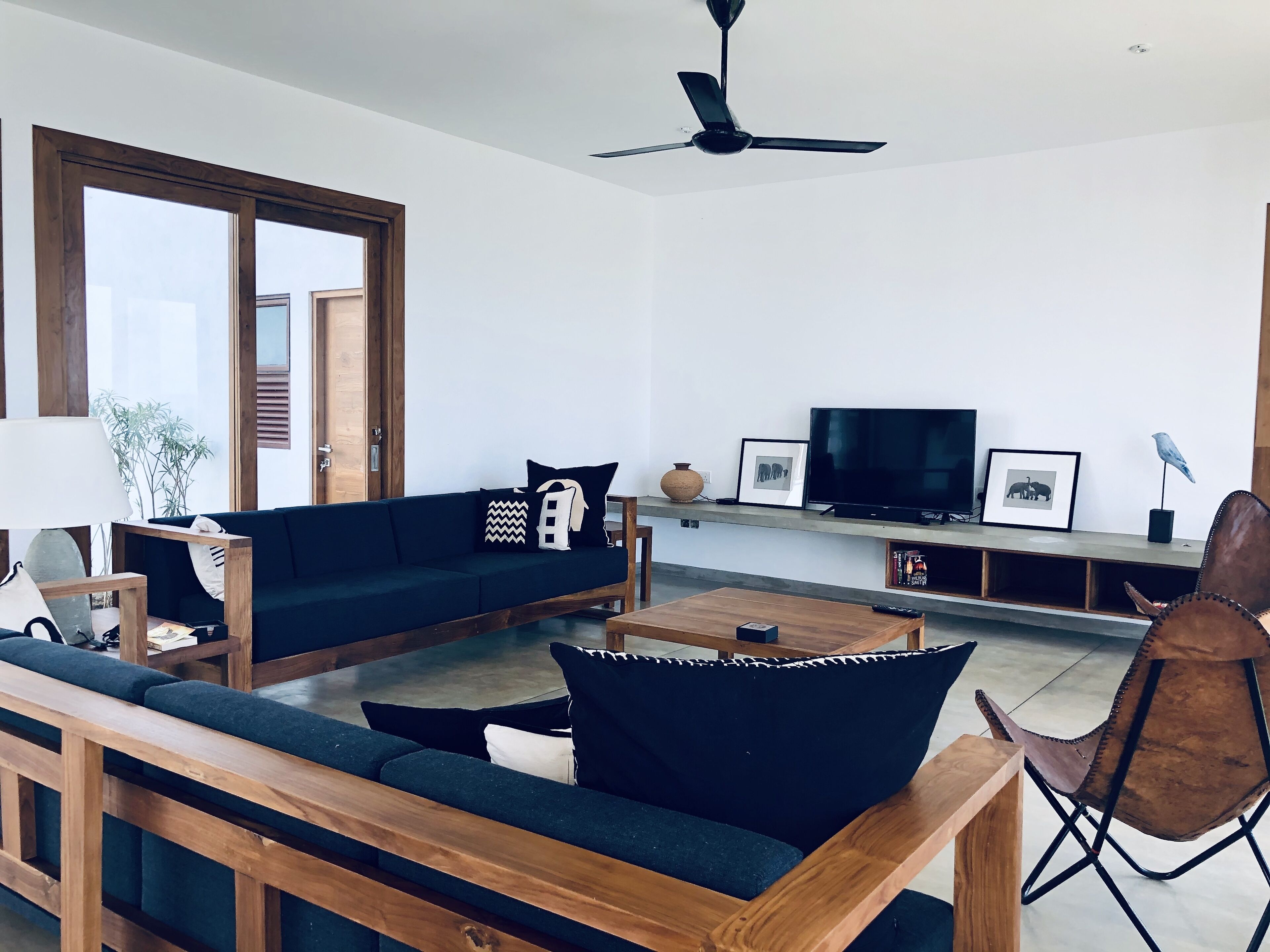 Un salon moderne avec un canapé vert foncé, une table basse en bois et un ventilateur de plafond.