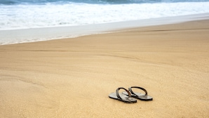 A pair of flip-flops on a sandy beach with ocean waves in the background. - Villa Tanderra (Kalametiya)
