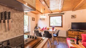 A modern kitchen with a tiled backsplash, wooden ceiling beams, and a dining area with a table and chairs. - Modern family&pet friendly villa with private sauna and beach (Bosljiva Loka)