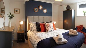 A bedroom with a bed, bedside tables, a dresser, a wardrobe, and a window with a plant. - Bay View - Amazing Location ,dog friendly, 10 mins to the beach and town. (Scarborough)