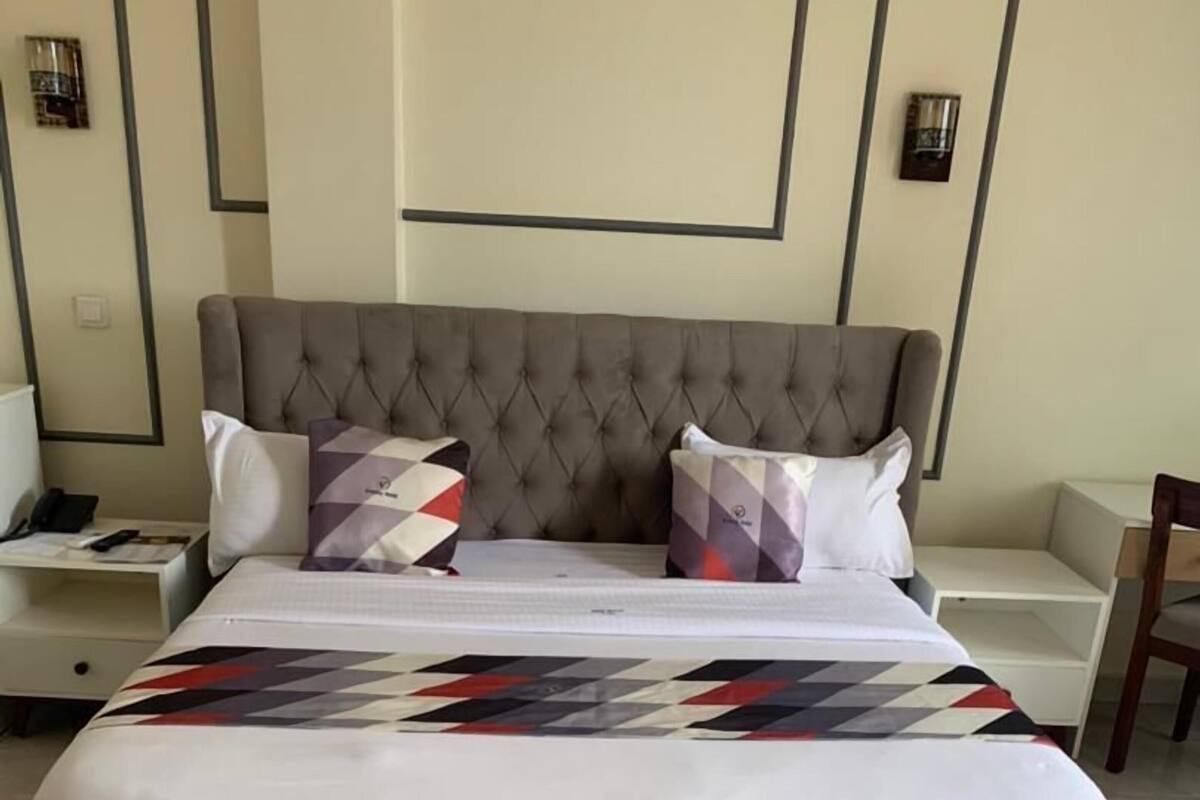 Una cama con colcha, dos almohadas, una mesita de noche y una silla.