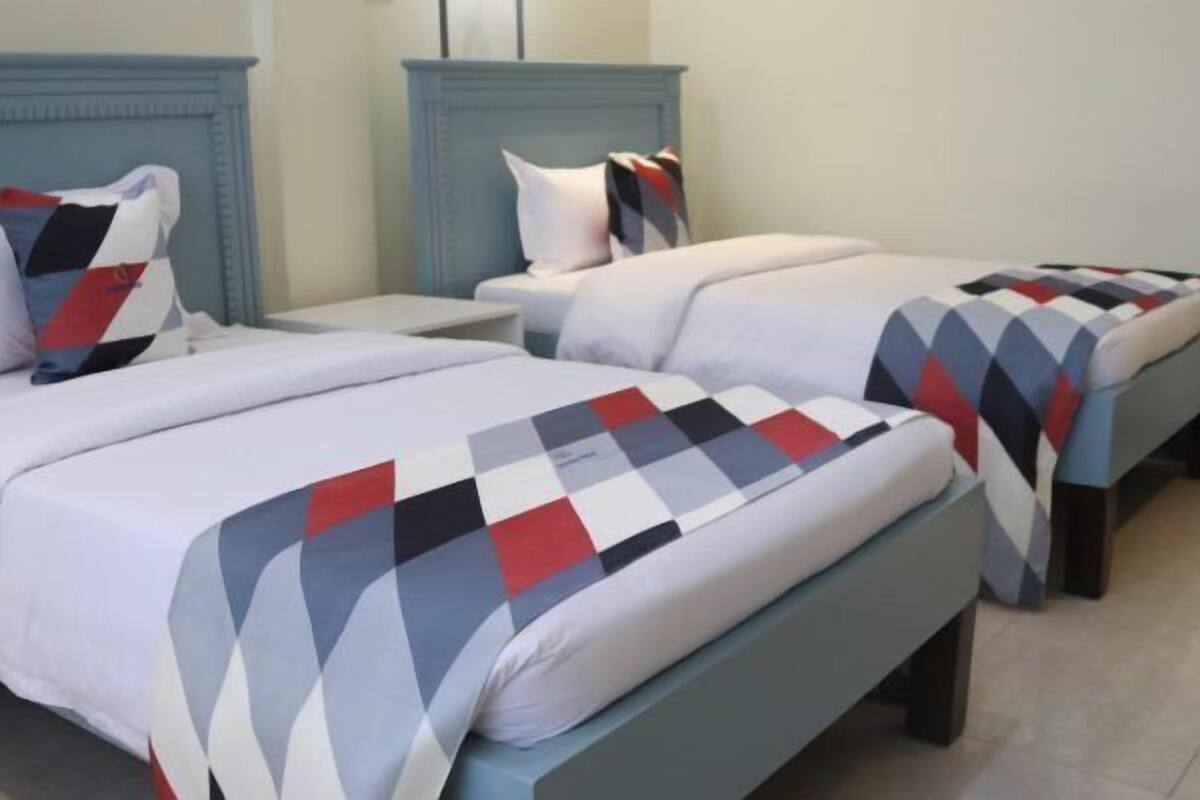Habitación de hotel con dos camas, cada una con una colcha estampada y almohadas a juego.