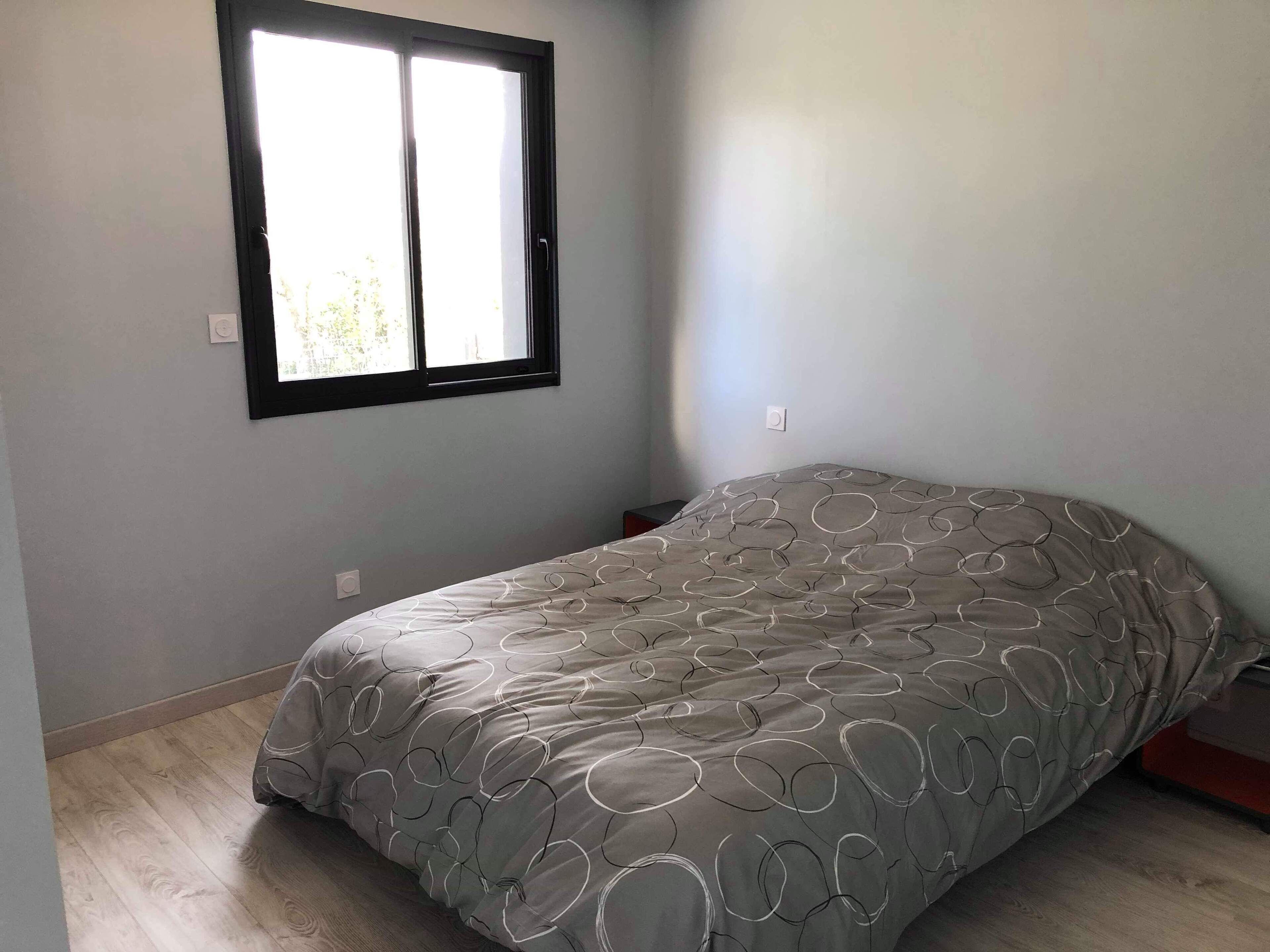Une chambre à coucher avec un lit, une fenêtre et un interrupteur sur le mur.