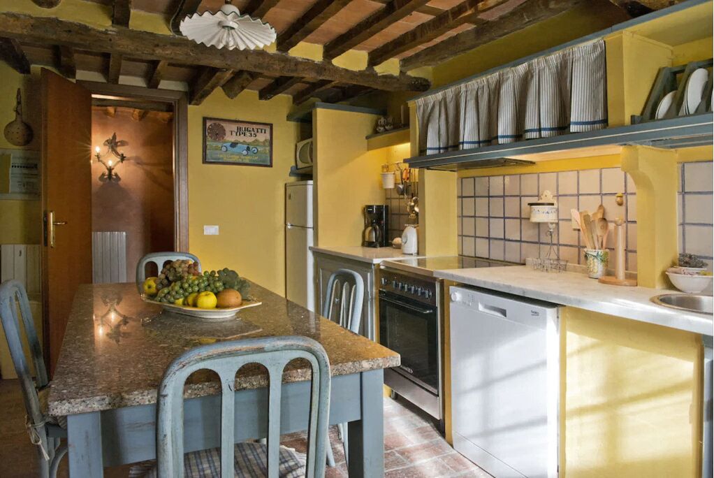 A kitchen with a granite countertop, a dining table with chairs, a refrigerator, an oven, and a sink.