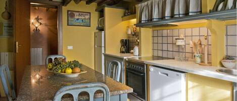 A kitchen with a granite countertop, a dining table with chairs, a refrigerator, an oven, and a sink.