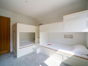 Una habitación con literas, una puerta de madera y piso alfombrado.