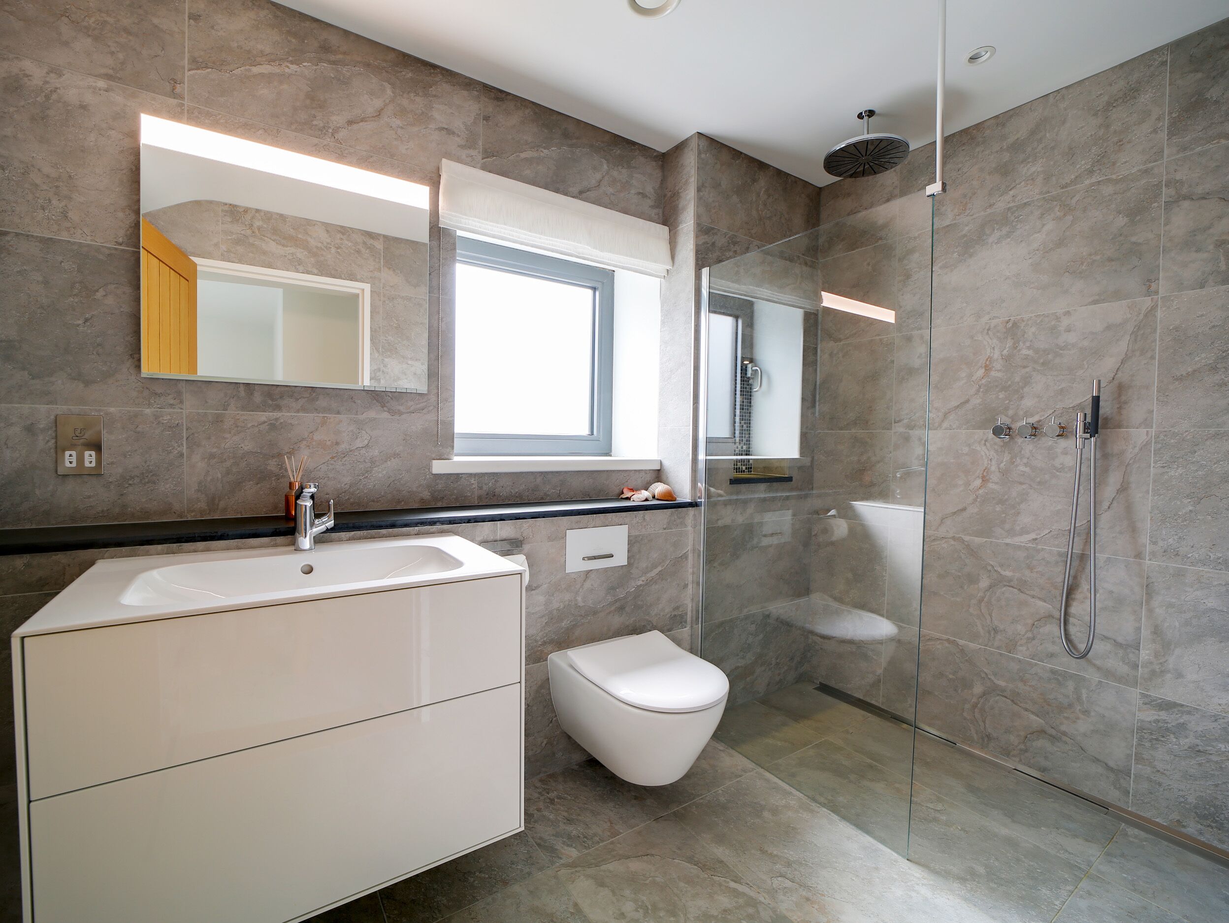 Une salle de bain moderne avec une douche à parois de verre, un meuble-lavabo blanc et un grand miroir.