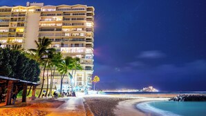 A beachfront hotel with multiple balconies, palm trees, and a view of the ocean. - LUXURY DIRECT OCEANFRONT! Fully Renovated! Free Parking! Sleeps 6 (Honolulu)
