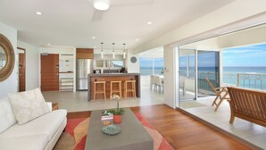 A modern living room with a sofa, coffee table, and a view of the ocean through large glass doors. - LUXURY DIRECT OCEANFRONT! Fully Renovated! Free Parking! Sleeps 6 (Honolulu)