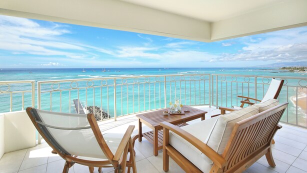 A balcony with a view of the ocean, wooden furniture, and a table with a drink. - LUXURY DIRECT OCEANFRONT! Fully Renovated! Free Parking! Sleeps 6 (Honolulu)
