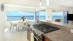 A modern kitchen with a large island, a dining area, and a view of the sea. - LUXURY DIRECT OCEANFRONT! Fully Renovated! Free Parking! Sleeps 6 (Honolulu)