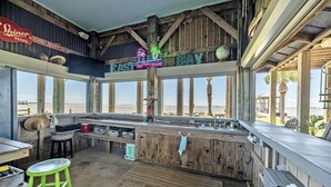 A beachside bar with wooden interiors, a neon sign for 'The Pink House', and a view of the ocean. - Beach House on the Bay - Fisherman's Paradise on the bay! (Port Bolivar)