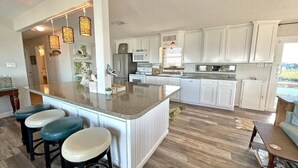 A spacious kitchen with a central island, white cabinetry, and a wooden floor. - Beach House on the Bay - Fisherman's Paradise on the bay! (Port Bolivar)