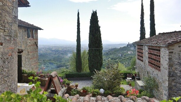 A stone building with a courtyard, a view of the countryside, and tall cypress trees. - IL FORNO - Wonderful stone rustic house in the hills with breathtaking views. (Matraia)