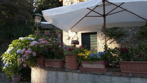 A stone building with a white umbrella, potted plants, and a lantern. - IL FORNO - Wonderful stone rustic house in the hills with breathtaking views. (Matraia)