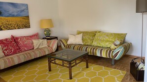 A living room with two sofas, a coffee table, a lamp, and a painting on the wall. - Bijou Apartment (Zollikofen)