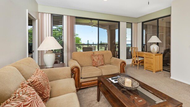 A living room with a sofa, coffee table, and a dining area with a table and chairs. - Summer Deal Golfers Paradise Condo with Fairway and Ocean Views (Waikoloa)