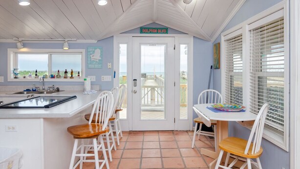 Una cocina con vista al océano, un comedor con sillas blancas y un letrero que dice "DOLPHIN BLVD".