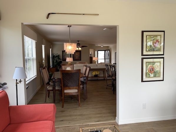 A spacious living area with a dining table, chairs, a red sofa, and a chandelier.