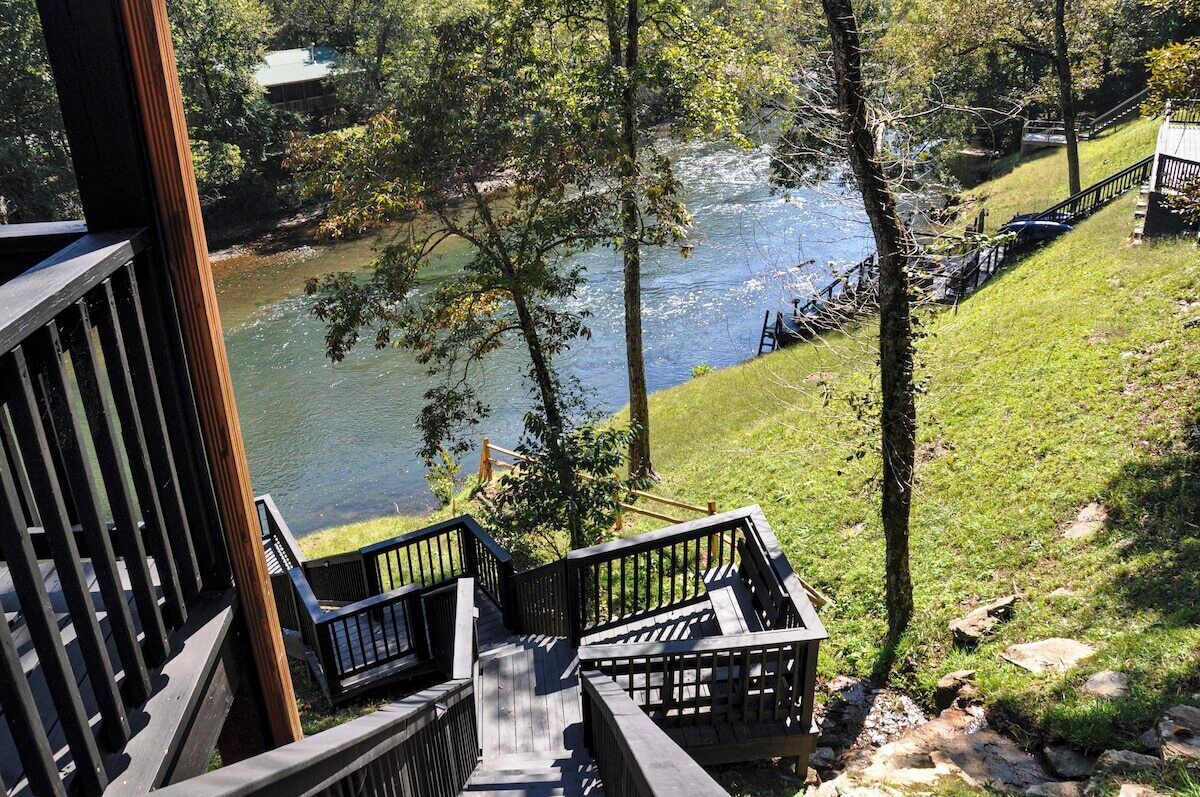 A wooden deck with a view of a river and a grassy area.