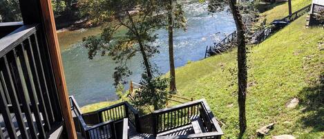 A wooden deck with a view of a river and a grassy area.
