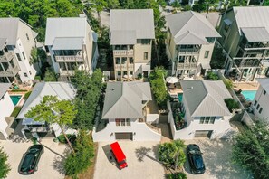 Vista aerea di una zona residenziale con diverse case a due piani, ognuna dotata di portico e piscina.