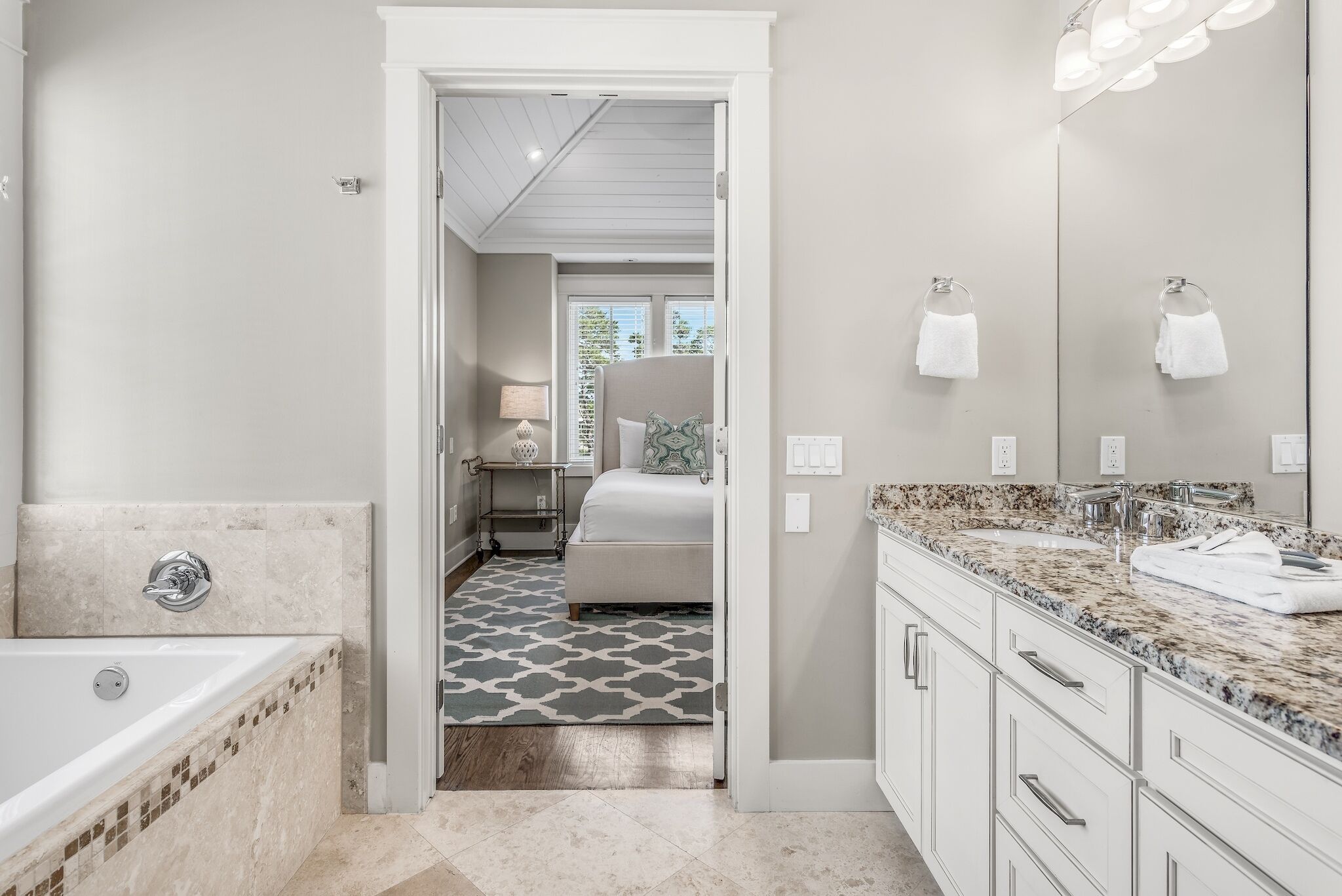 A modern bathroom with a bathtub, vanity, and a large mirror.