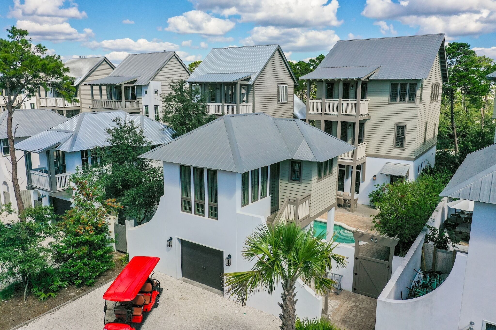 A row of modern, two-story houses with flat roofs and balconies, surrounded by greenery.