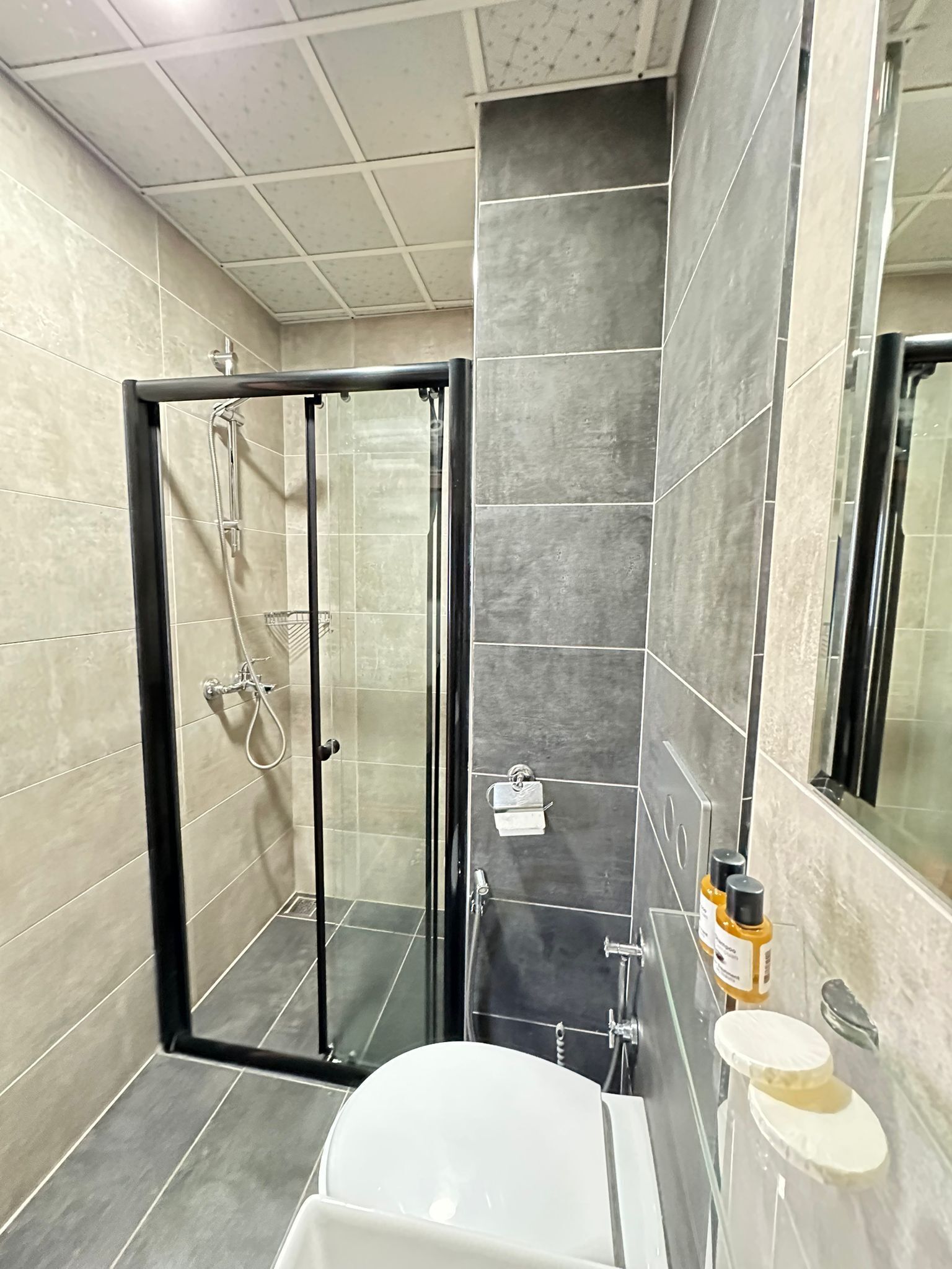 Un baño moderno con ducha envuelta en vidrio, bañera blanca y tocador con artículos de aseo.