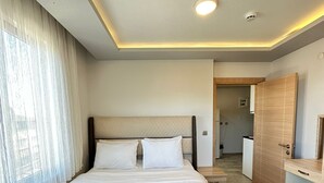 Una habitación de hotel moderna con una cama grande, una mesita de noche, un armario y un baño visible a través de una puerta abierta.