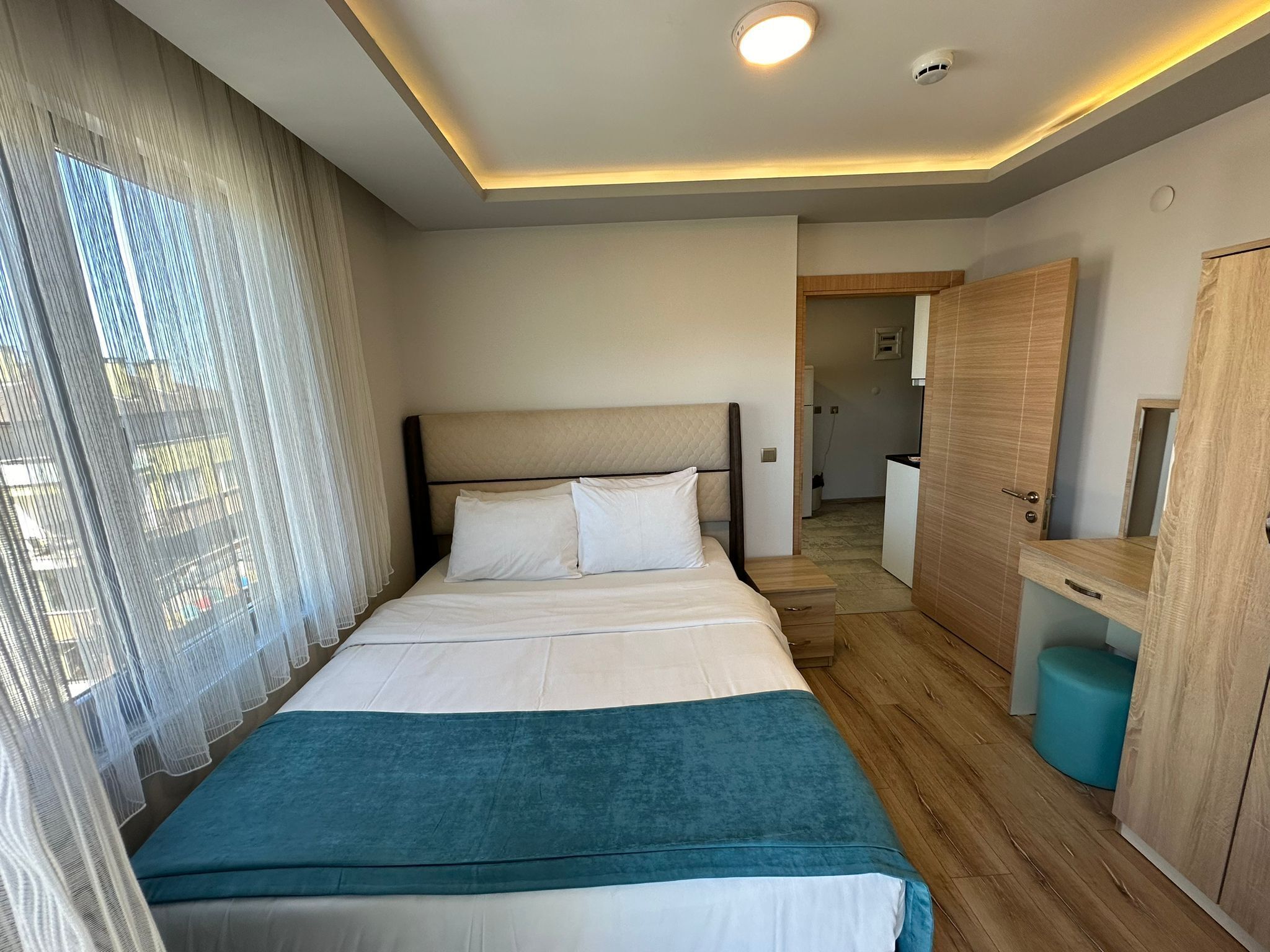 A modern hotel room with a large bed, a desk, and a mirror.