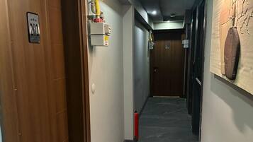 A hallway with a wooden door labeled "202," a fire extinguisher, and an exit sign.