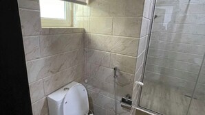 A bathroom with a toilet, a shower, and a window. - Lovely luxury 3 bedroom apartment (Lagos)
