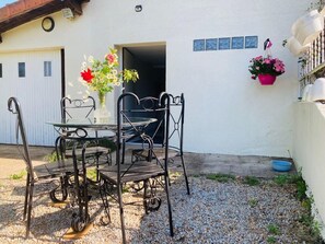 Un juego de comedor exterior de metal con sillas y una mesa, un florero y un macramé colgante con flores.