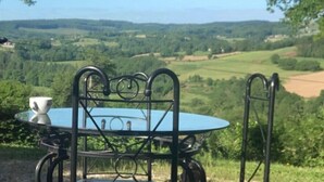 Ein Tisch mit Metallgestell und Glasplatte, eine weiße Tasse und ein Fahrrad, das daneben abgestellt ist.
