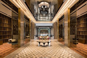 A spacious lobby with a geometric patterned floor, a central table with floral arrangements, and bookshelves on either side. - Radisson Blu Hotel & Spa, Nashik (Nashik)
