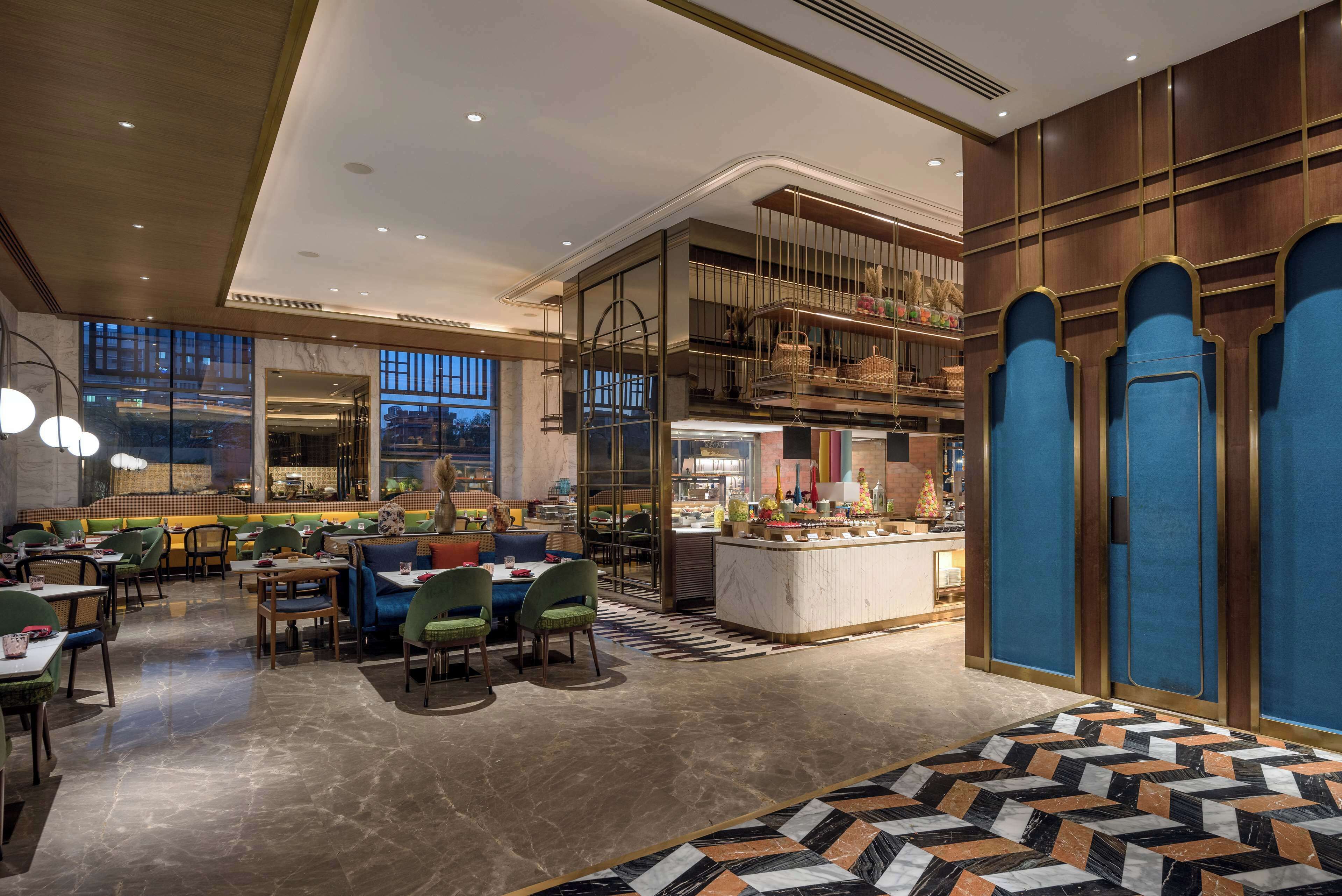 A modern restaurant with a high ceiling, marble flooring, and a variety of seating options including booths and tables.