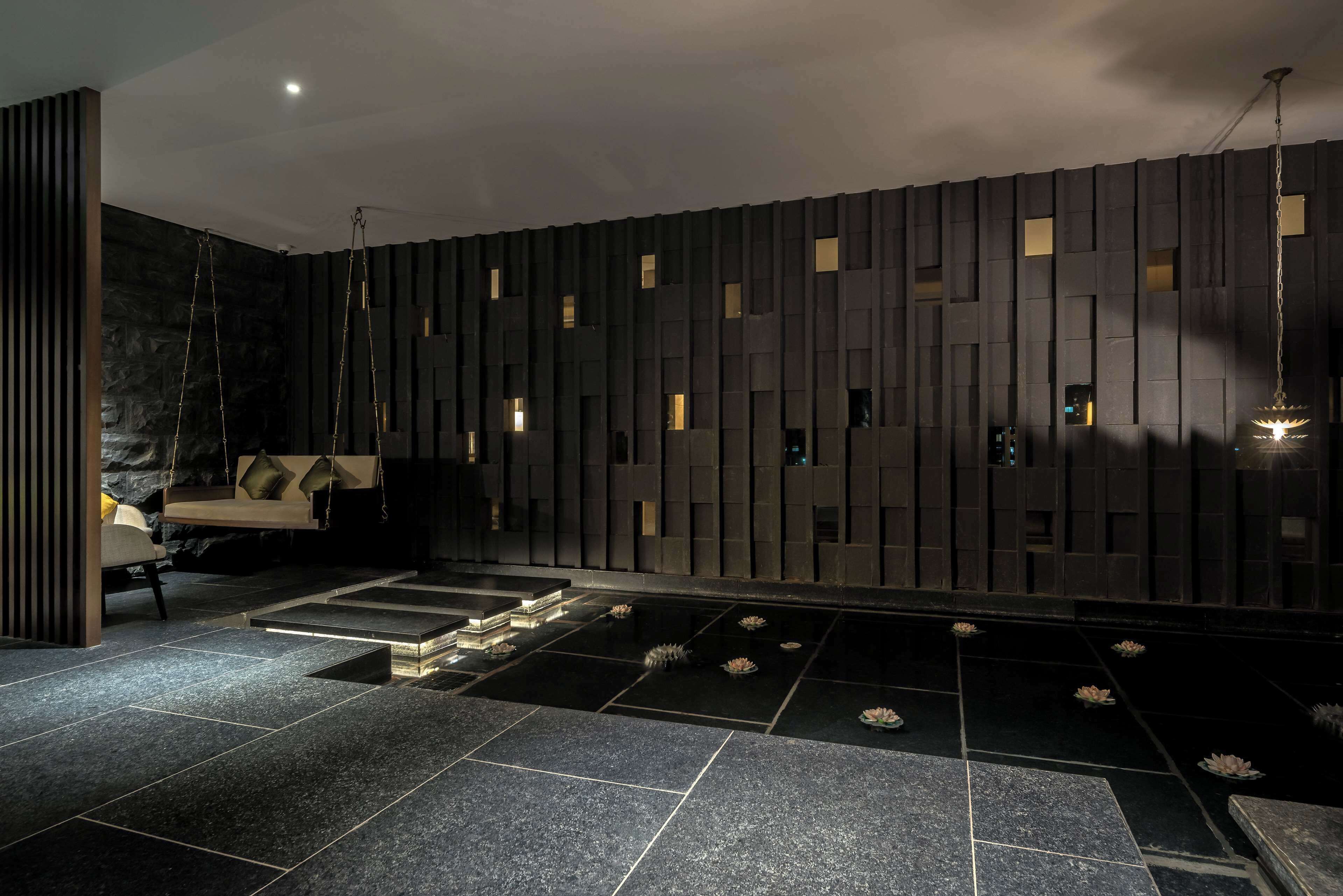 A modern interior with a stone wall, a suspended seating area, and a water feature.